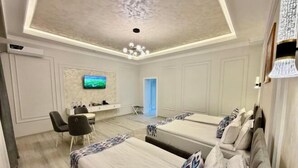 A modern hotel room with two beds, a desk, a TV, and a ceiling light fixture. - Isakhoja Hotel (Khiva)