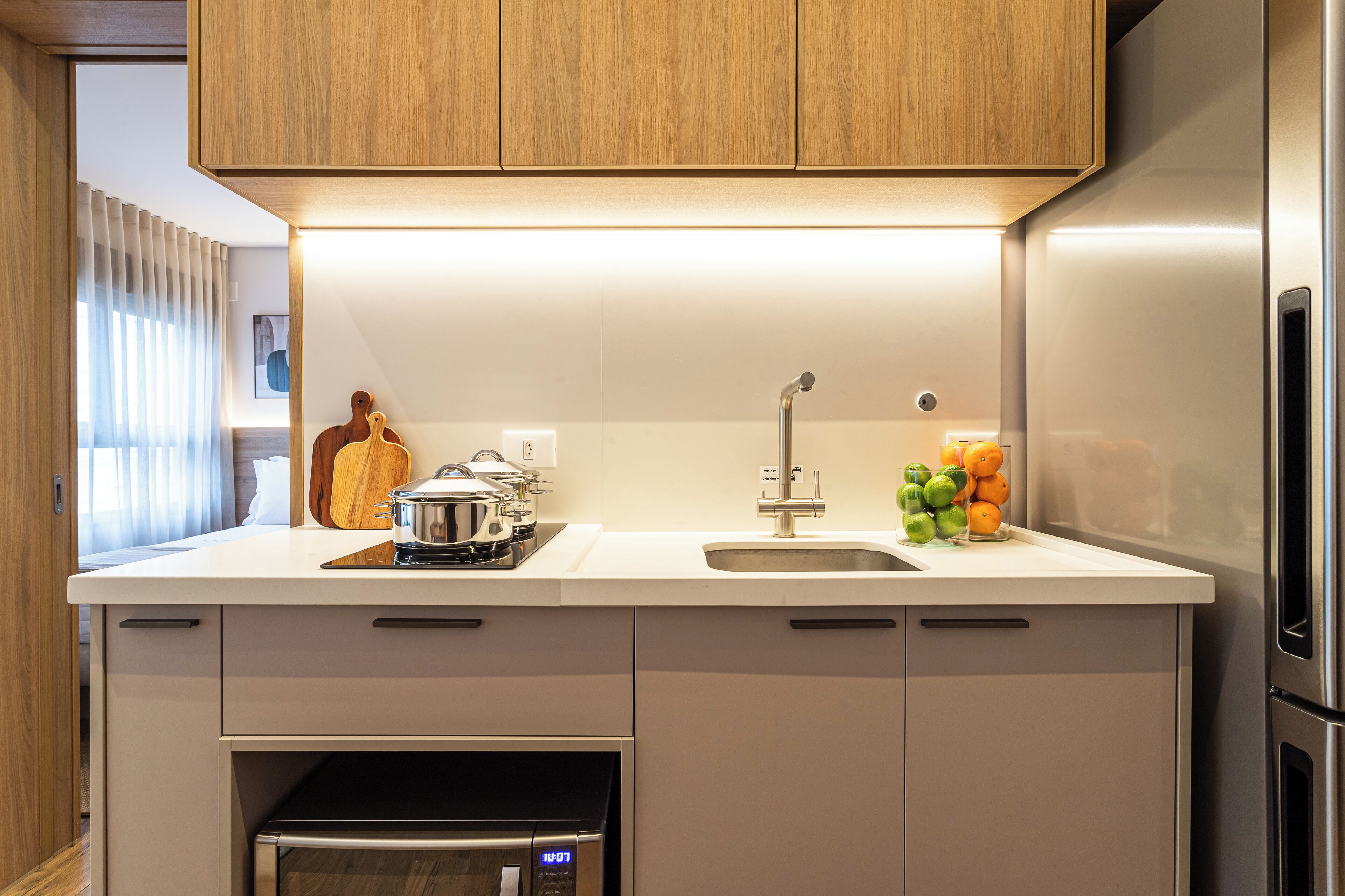 A modern kitchen with a built-in oven, a stainless steel refrigerator, and a sink with a faucet.