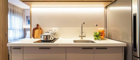 A modern kitchen with a built-in oven, a stainless steel refrigerator, and a sink with a faucet.