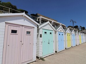 A row of colorful beach huts with a sloped roof and a small window on each hut. - The Granary (Axminster)
