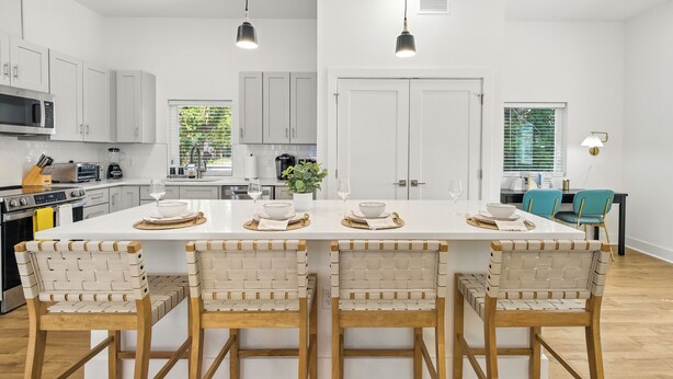 Een moderne keuken met witte kasten, een centraal eiland met barkrukken en hanglampen.