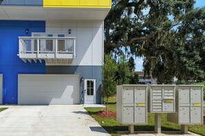 Un edifici modern amb façana blava i blanca, un balcó blanc i una porta de garatge.