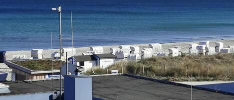 A beachside property with a parking area, beach huts, and a view of the ocean.