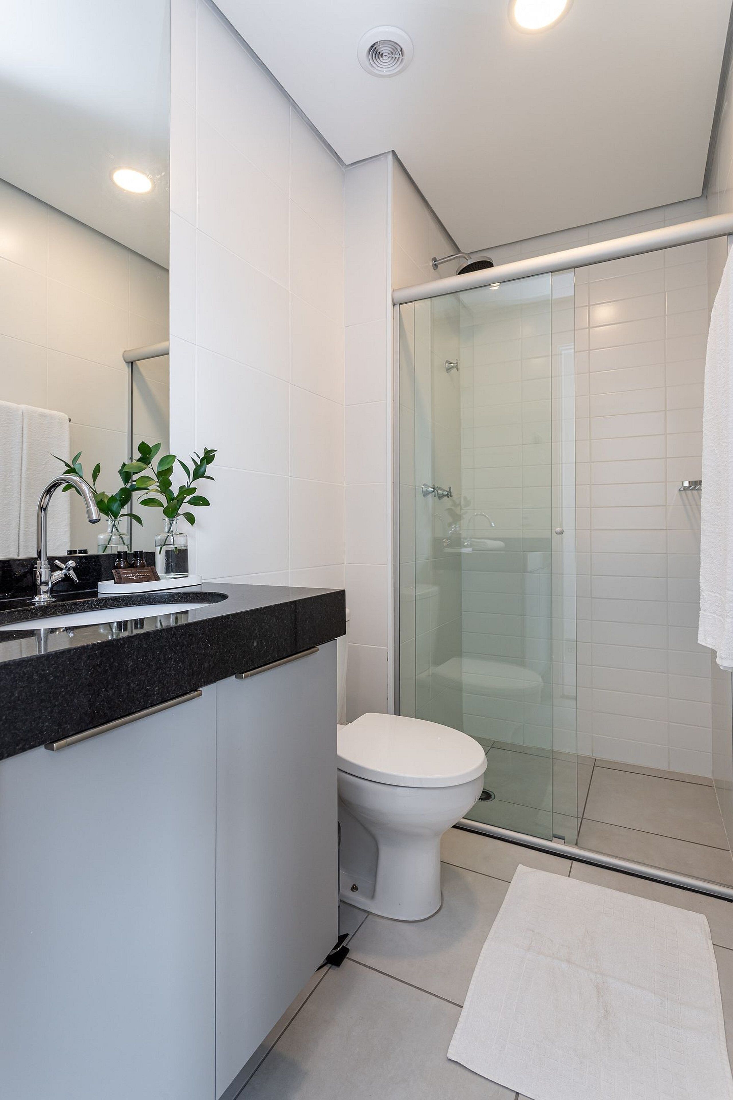 A modern bathroom with a glass shower enclosure, a white toilet, and a black countertop with a sink.