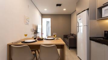 A modern kitchen with a refrigerator, microwave, and dining area with two chairs and a table set for two.