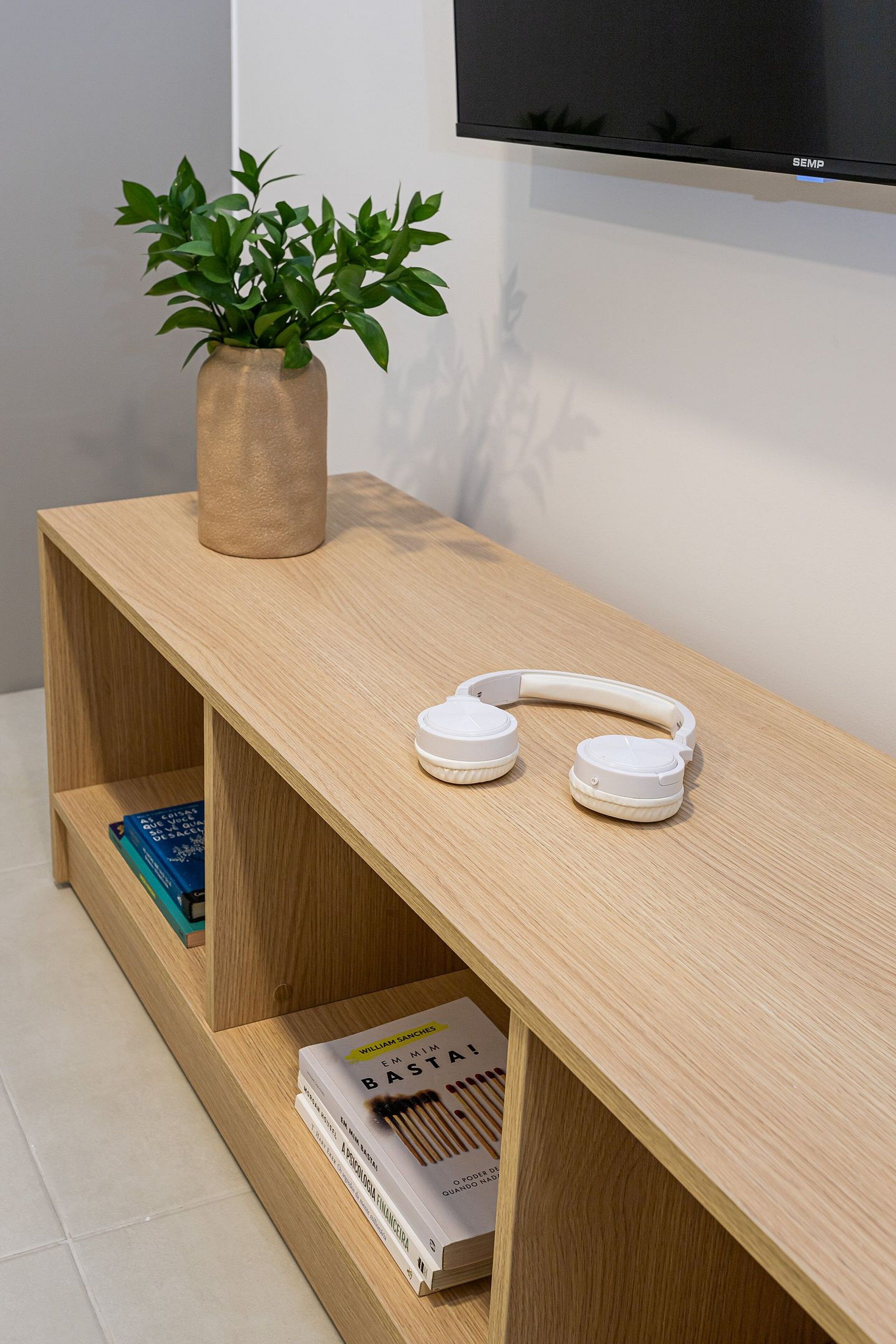 A wooden shelf with a potted plant, a pair of headphones, and books.