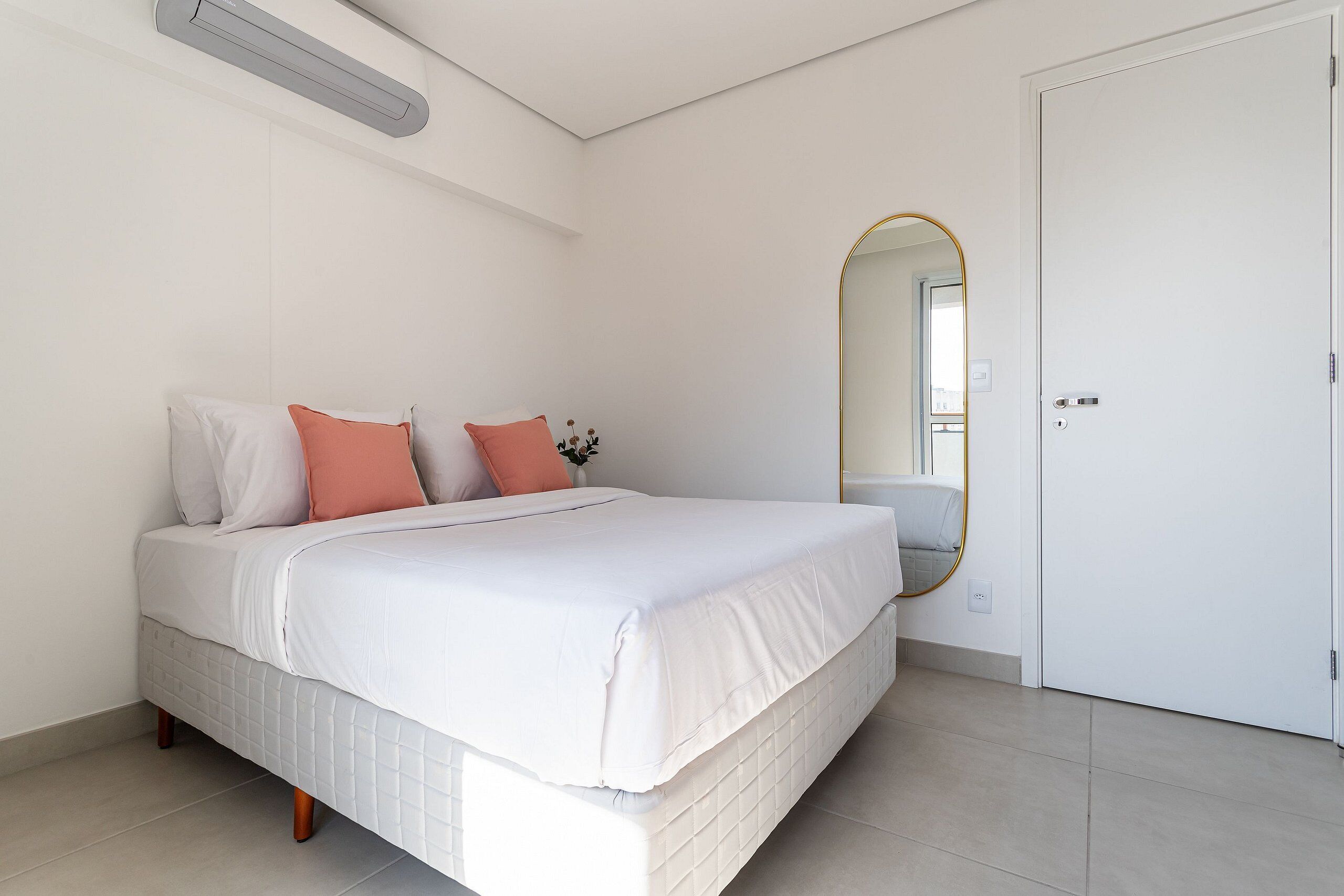 Un dormitorio con cama, puerta y espejo instalado en la pared.