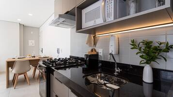 Una cucina moderna con un piano di lavoro nero, elettrodomestici in acciaio inossidabile e un forno a microonde integrato.
