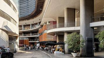 Un centro comercial de varios niveles con techo curvo, pilares grandes y zonas de estar al aire libre.