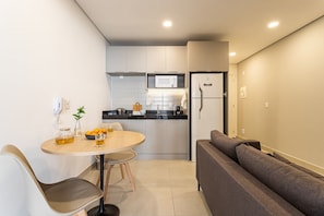 Una cocina compacta equipada con microondas, refrigerador y un comedor con mesa y sillas.