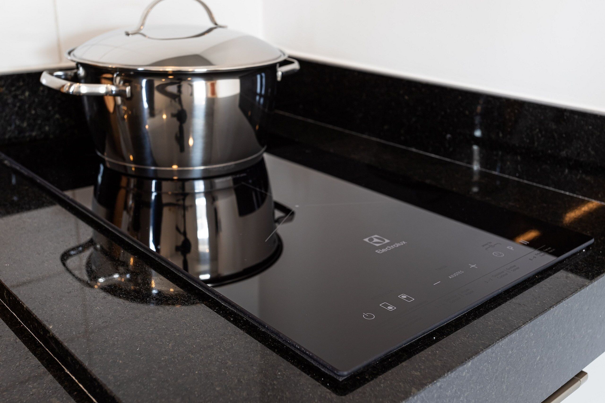 A black induction cooktop with a pot on it.