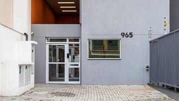A modern building with a ground-level entrance, a visible number '965', and a tiled pavement.