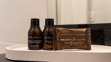 Tres botellas de champú, acondicionador y jabón MELÃO & Jasmin sobre una encimera de baño.