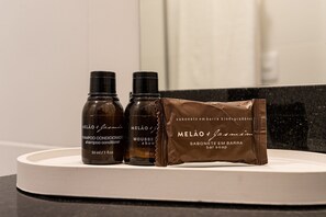 Tre bottiglie di shampoo, balsamo e sapone MELÃO & Jasmin su un ripiano del bagno.