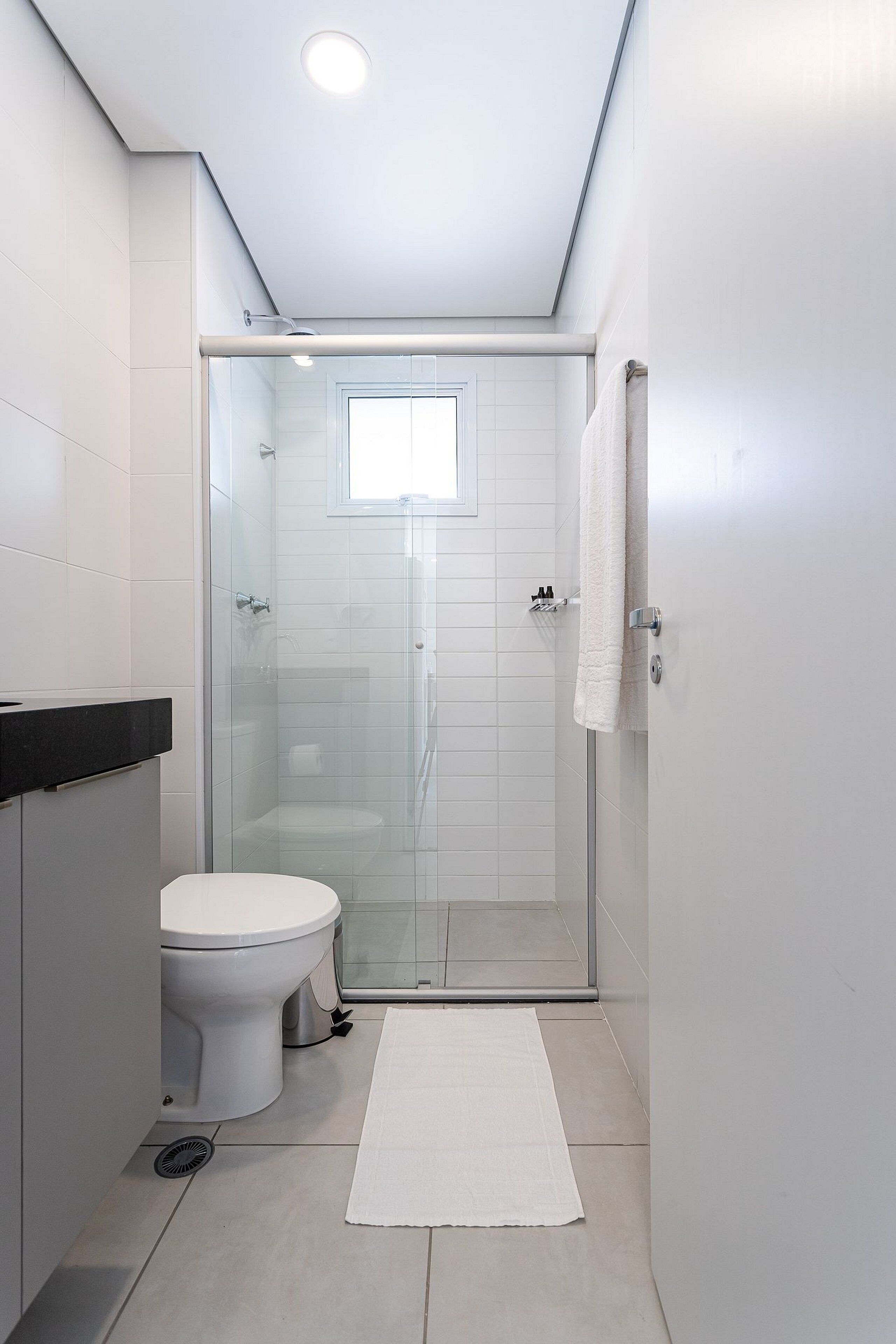 A modern bathroom with a glass-enclosed shower, a white toilet, and a black countertop.