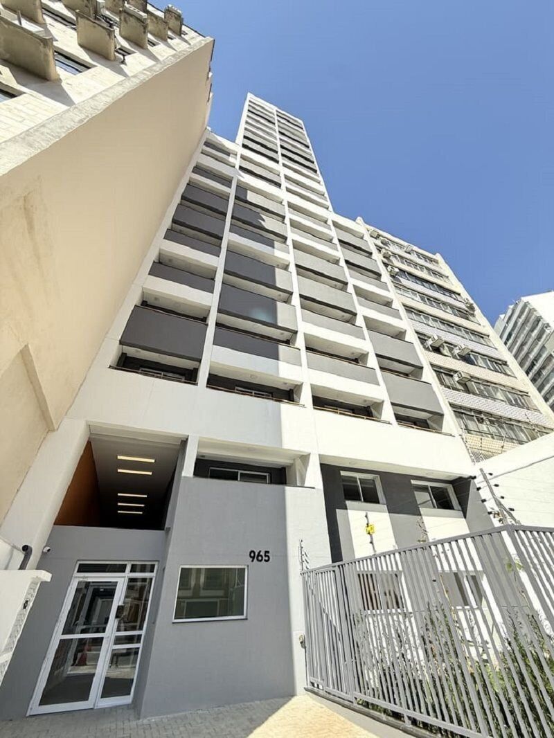 A modern high-rise building with a prominent entrance, numbered 965, and a gated driveway.
