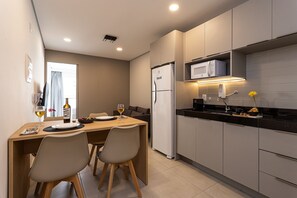 Una cocina moderna con comedor. Incluye refrigerador, microondas y una mesa de comedor con sillas.