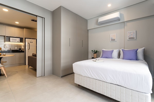 Un dormitorio moderno con cama, mesita de noche y un pequeño escritorio con silla.