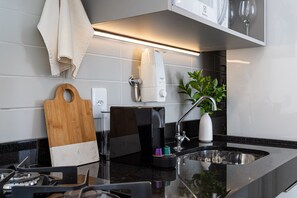 Een moderne keuken met een zwart aanrecht, een koffiezetapparaat, een snijplank en een spoelbak.