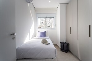 Een slaapkamer met een bed, een raam, een deur en een tas.