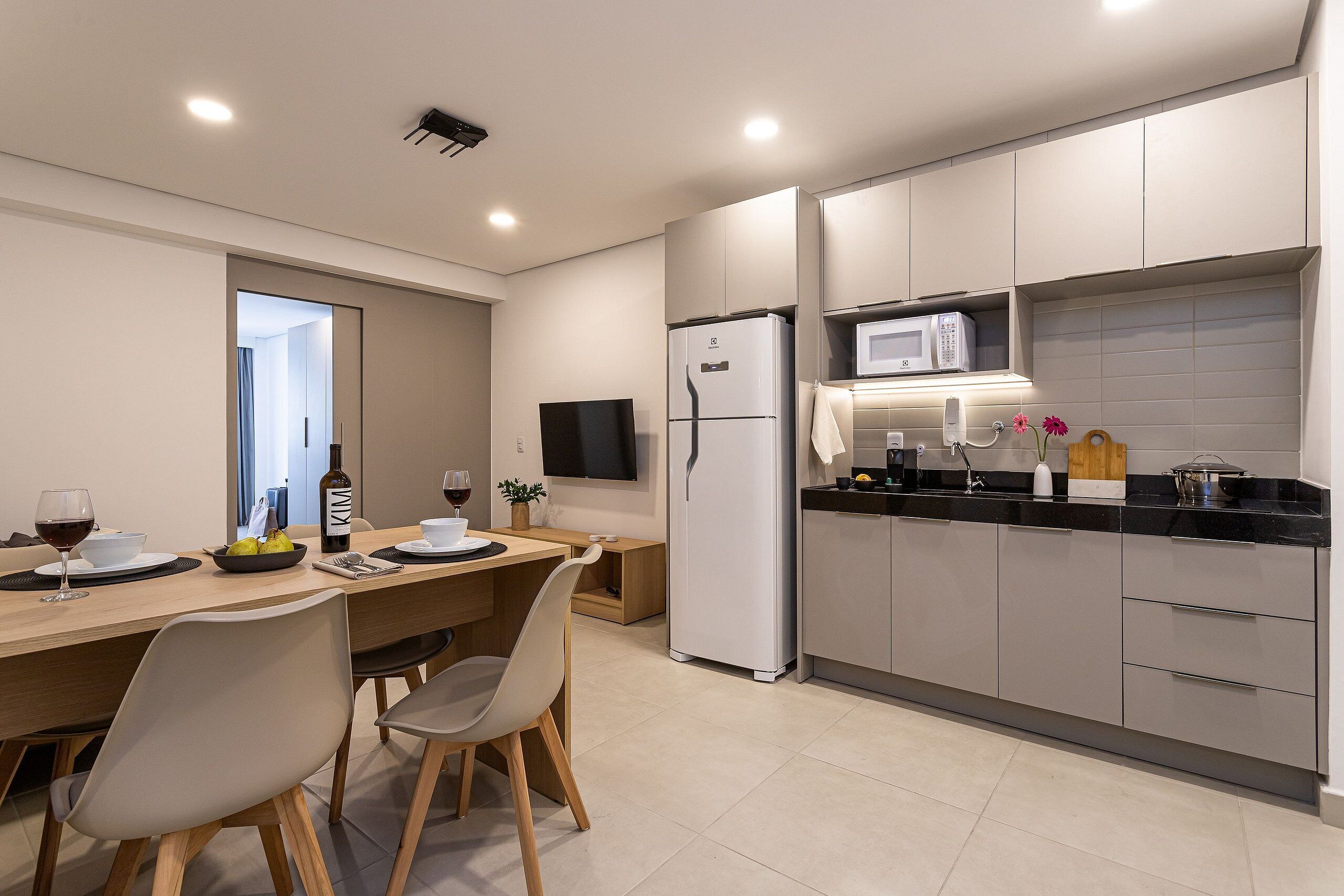 Una cocina moderna con comedor, que incluye un refrigerador, microondas y una mesa con sillas.