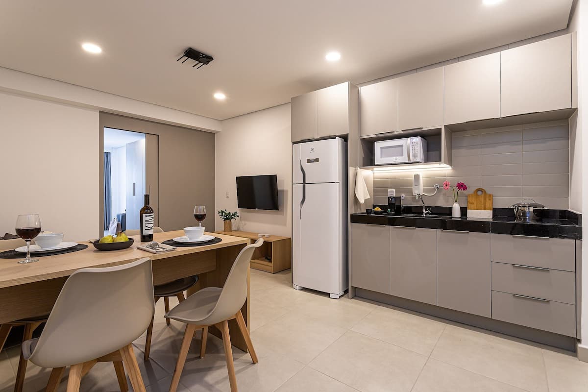Una cocina moderna con comedor, que incluye un refrigerador, microondas y una mesa con sillas.