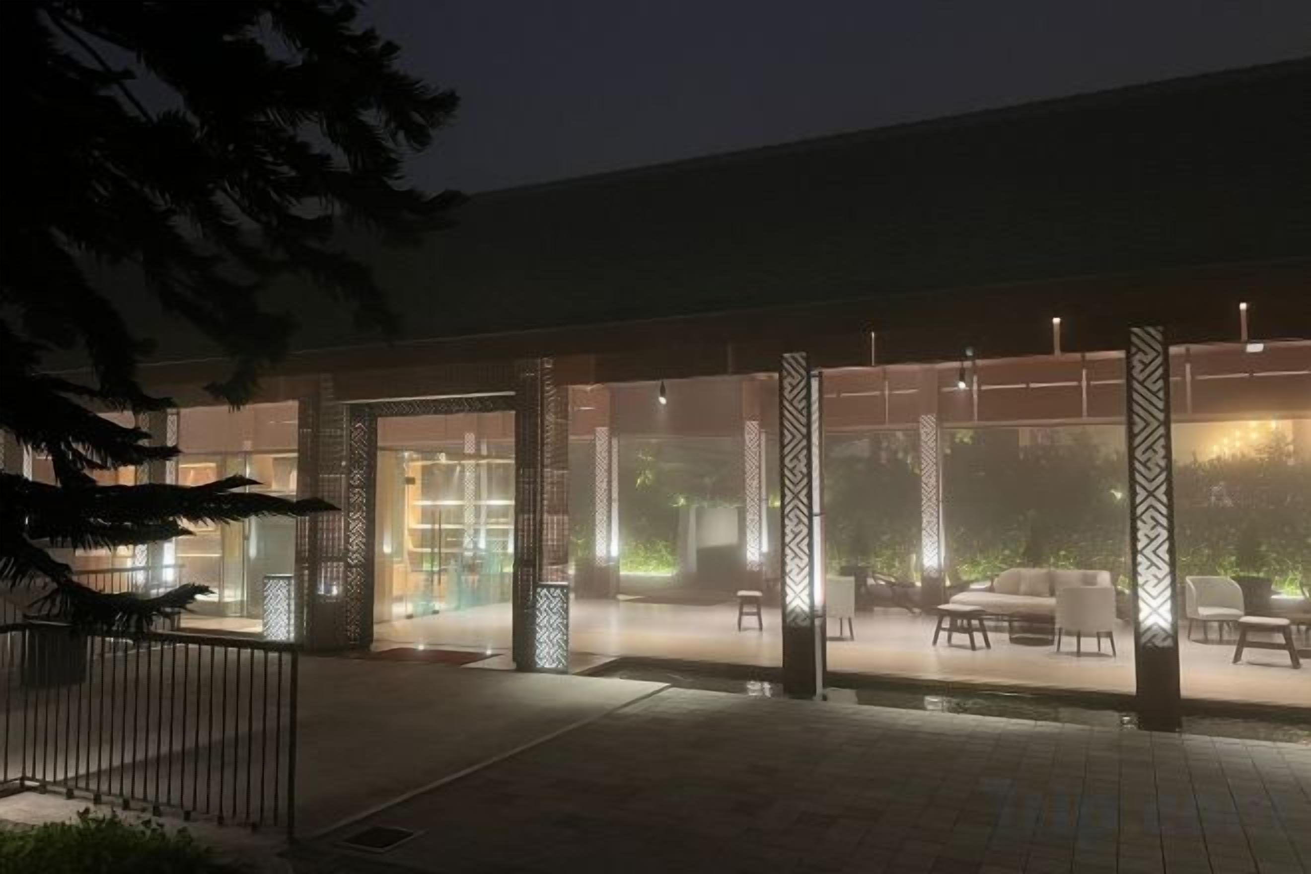 An outdoor seating area with tables and chairs, a water feature, and a building entrance with glass doors.