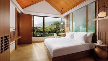 A modern bedroom with a large bed, wooden ceiling, and a view of greenery outside.