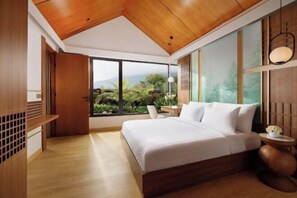 Un dormitorio moderno con una cama grande, techo de madera y vistas a zonas verdes.