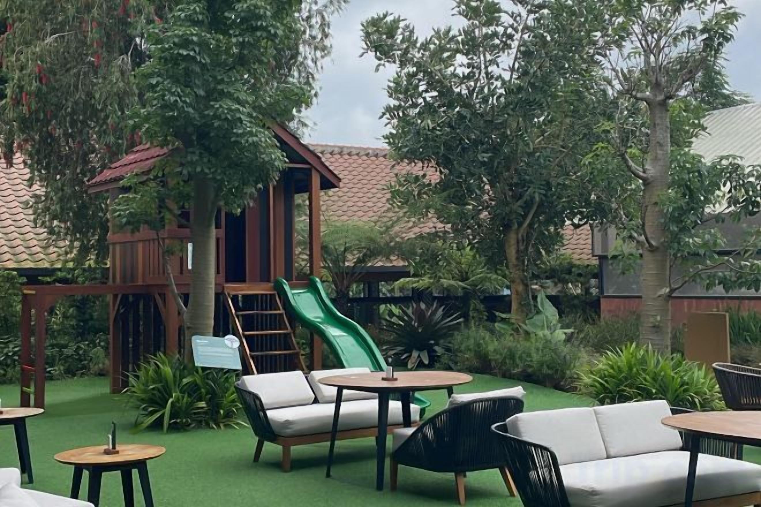 An outdoor seating area with tables and chairs, a slide, and a wooden play structure.