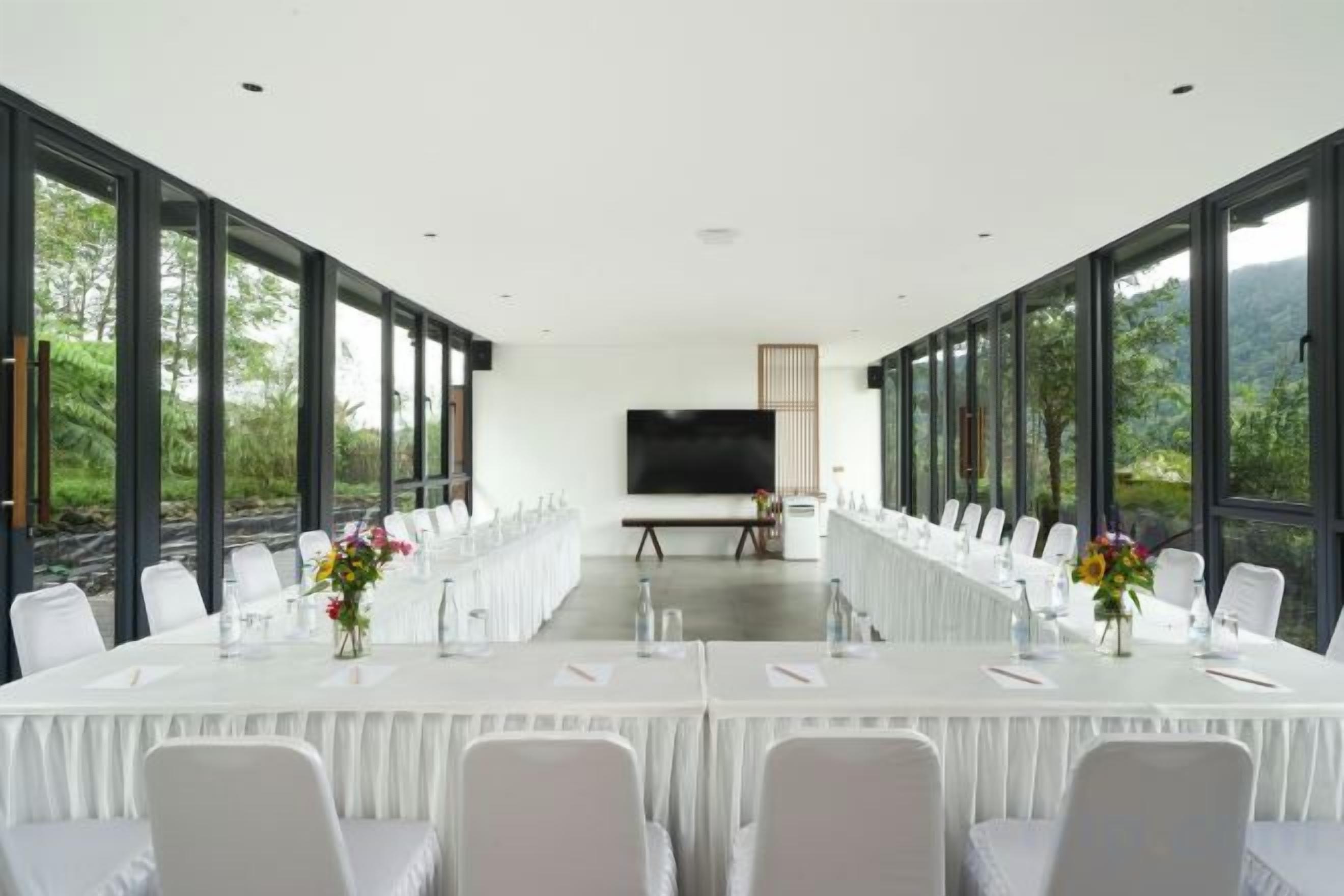 A conference room with a long table, chairs, and a large screen.