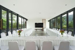 Un salón de conferencias con una larga mesa, sillas y una pantalla grande.