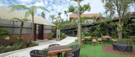 A courtyard with a green lawn, outdoor seating, and a building with a red roof.
