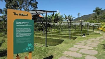Un cartel con texto y un jardín con senderos y plantas.