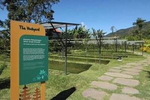 Un cartel con texto y un jardín con senderos y plantas.