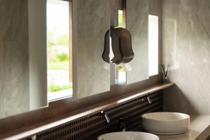Un baño con lavamanos, dispensador de toallas y ventana que proporciona luz natural.