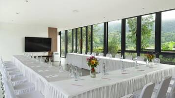 A conference room with a long table, chairs, a TV, and large windows with a view.