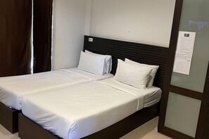 A double bed with white bedding, a dark headboard, and a glass partition with a notice on the wall. - Pichawaree Resort (Si Thep)