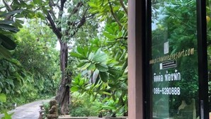 A restaurant with a glass wall offering a view of a lush garden. - Pichawaree Resort (Si Thep)