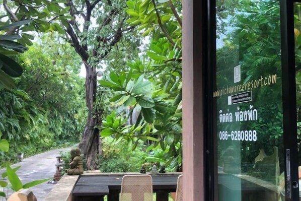 A restaurant with a glass wall offering a view of a lush garden. - Pichawaree Resort (Si Thep)