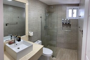 A modern bathroom with a glass-enclosed shower, a white sink, and a toilet. - Maple Beach Residences Punta Cana  (Punta Cana)