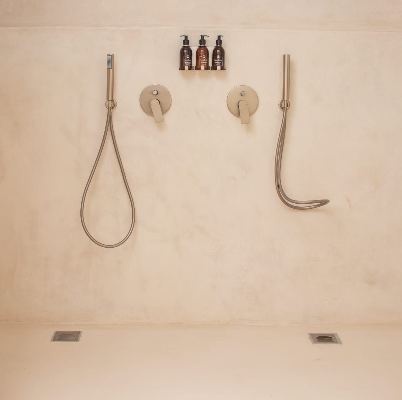 Un baño con ducha, dos grifos y tres botellas de champú.