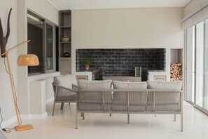 Un salon moderne avec un canapé, une cheminée et une grande fenêtre.