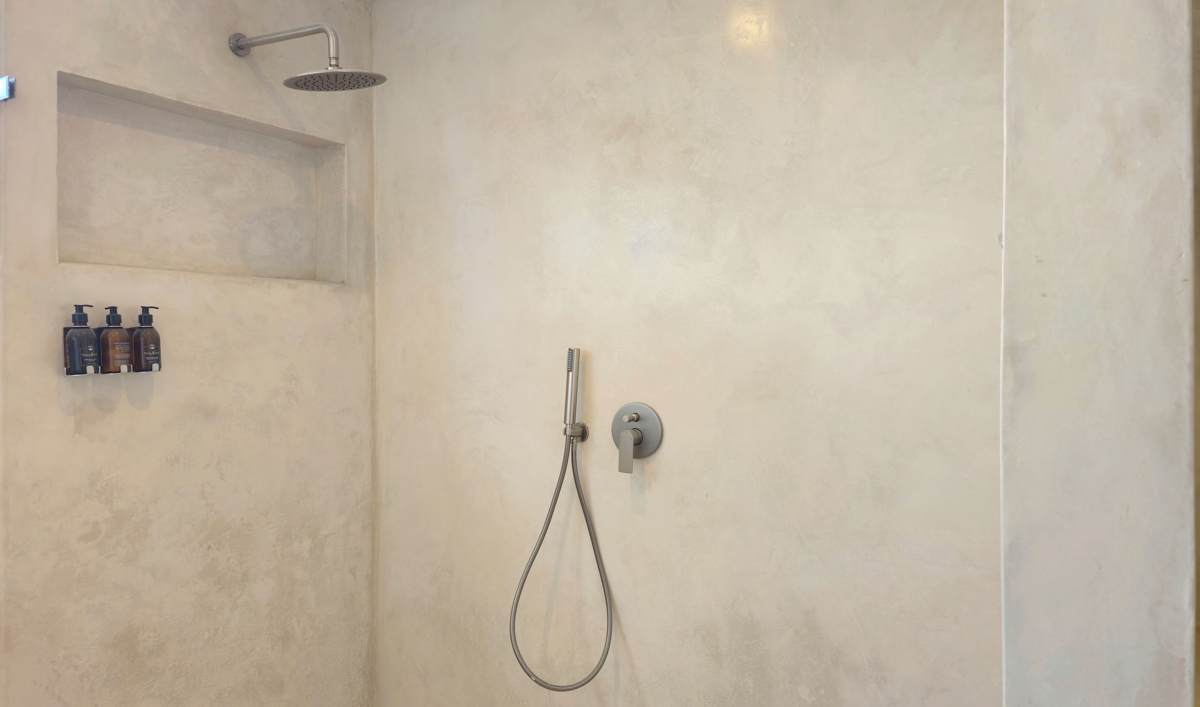 A shower with a handheld showerhead and a wall-mounted faucet.