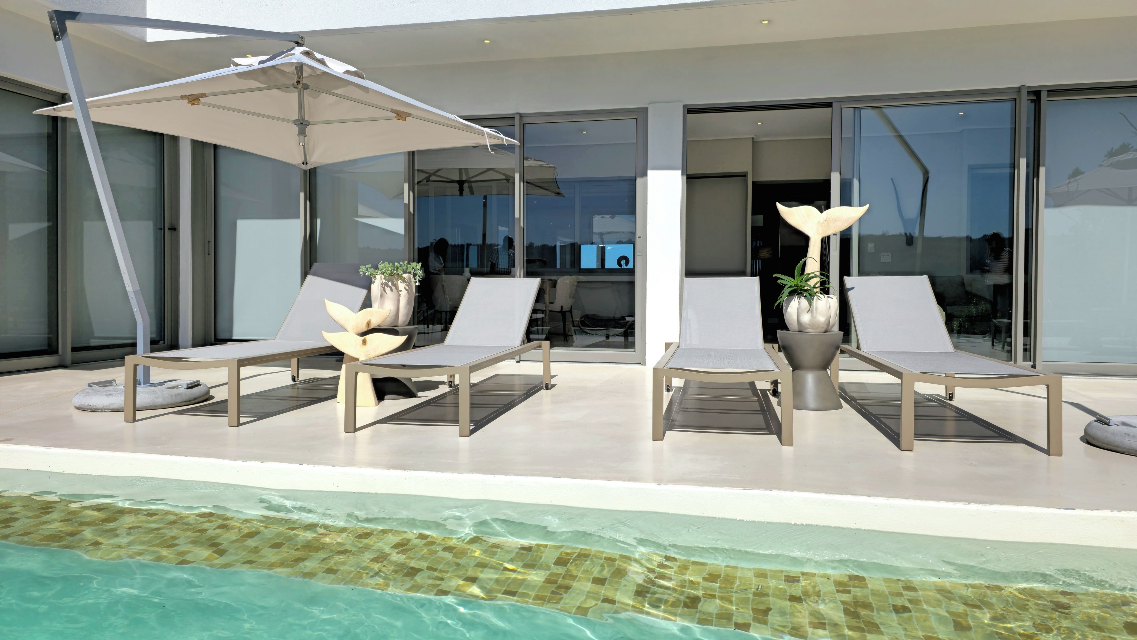Uma área moderna de piscina ao ar livre com espreguiçadeiras e guarda-sóis.