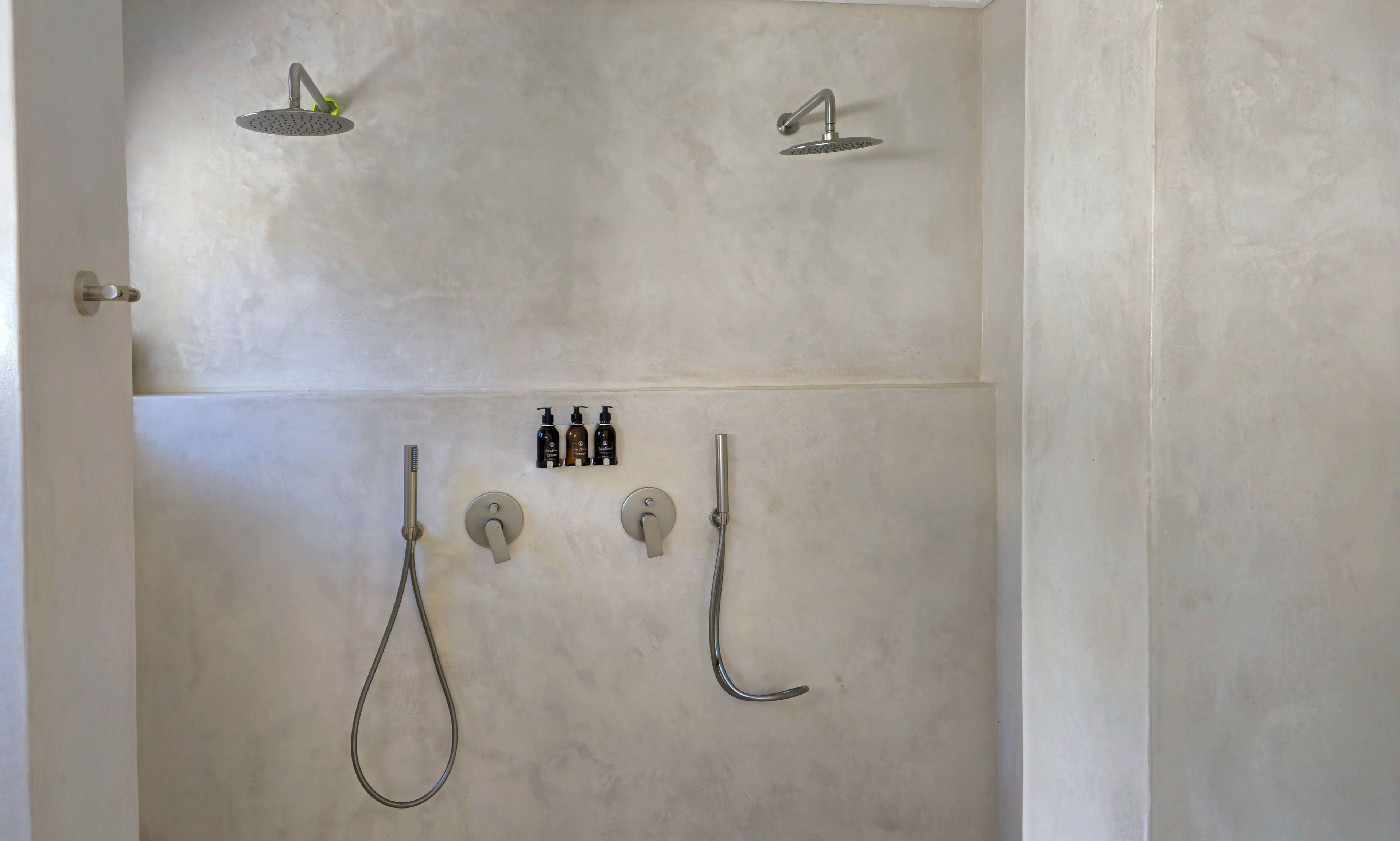 Une salle de bain avec une douche, deux robinets et trois bouteilles de shampoing et d’après-shampoing.