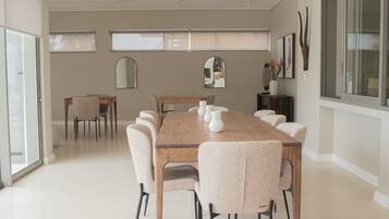A modern dining area with a wooden table, six chairs, and a long mirror above.