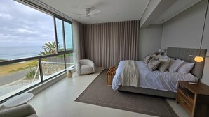 Een moderne slaapkamer met een groot bed, een stoel en uitzicht op de oceaan.