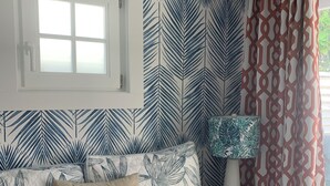 Une chambre à coucher avec un lit, une table de chevet, une lampe et une fenêtre avec des rideaux.