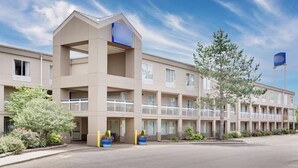 A multi-story hotel with a flat facade, balconies, and a parking lot. - Staywell Inn (Kalamazoo)